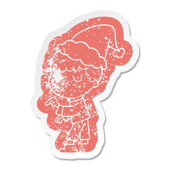 cartoon distressed sticker of a grumpy boy wearing santa hat