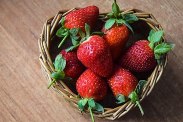 ripe red strawberries in a wicker basket in the form of a heart in the hands