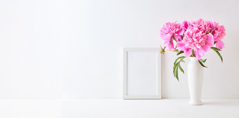 Mockup with a white frame and pink peonies in a vase on a white background