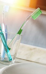 Toothbrushes in a glass cup on a sink vertical