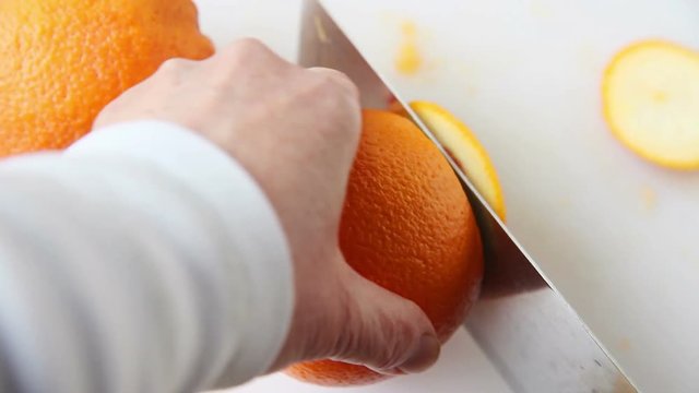 A woman cuts away the peel and part of the pith of a caracara orange