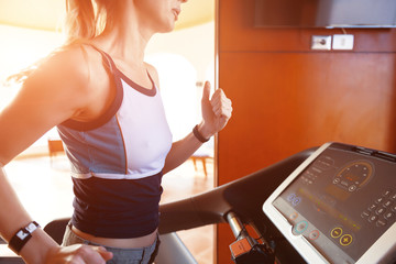 girl on the morning run on the treadmill in the gym in front of a large window on the background of the sea