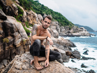 man sitting on a rock and looking at the sea