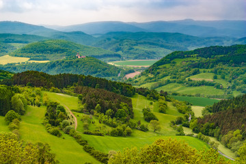Great panoramic landscape view at Hanstein Castle ruin which is surrounded by beautiful woodland, the Werra Valley and the Hessian low mountains. On the far left the Ludwigstein Castle can be seen. - obrazy, fototapety, plakaty