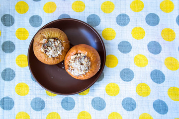 Baked Stuffed Apples on a Brown Saucer. Tablecloth in gray and yellow large peas.