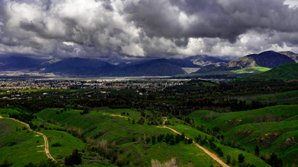 Fototapeta na wymiar Aerial, drone view of the emerald green Crafton Hills near Yucaipa, California after the rain with the San Bernardino Mountains and Seven Oaks Dam in the background