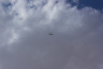 plane in sky on gray cloud background foreshortening from below flight travel concept wallpaper pattern photography with empty copy space for your text or inscription