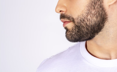 Obraz premium Handsome man in white t-shirt on a white background smiling, looking away, profile, close-up