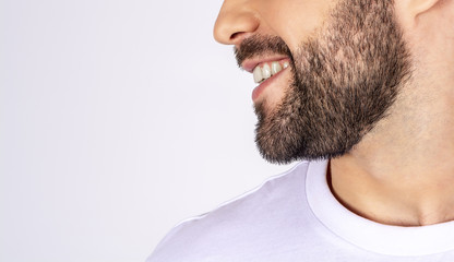 Obraz premium Handsome man in white t-shirt on a white background smiling, looking away, profile, close-up