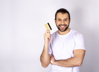 handsome man in a white T-shirt on a white background smiling, holding a credit card
