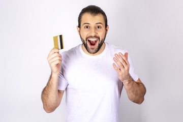 handsome man in a white T-shirt on a white background smiling, holding a credit card