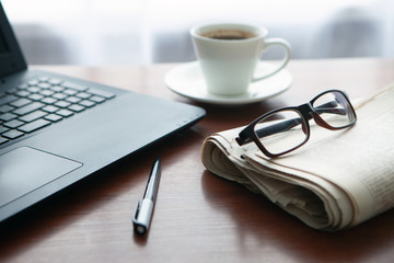 Newspaper with computer on table. Coffee break.