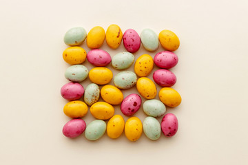 Easter chocolate eggs candy on a pastel yellow background, creative flat lay easter concept, top view