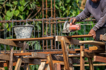 The asia worker cutting the wood by using electric saw while building the home