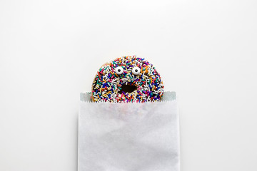 Funny shock face chocolate donut with sprinkles on a white background, creative minimal food concept