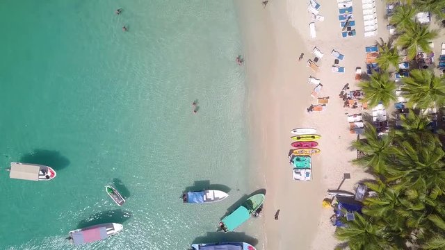 Aerial view looking down flying along a busy beach in the Western Caribbean in Roatan, Honduras.