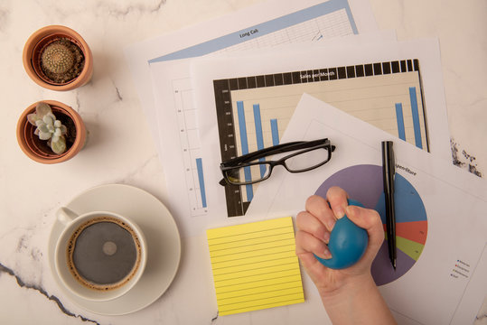 Busy Office Desk With Hand Squeezing Stress Ball