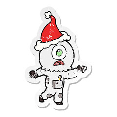 distressed sticker cartoon of a cyclops alien spaceman pointing wearing santa hat