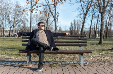 Happy man, Young happy guy with sunglasses and smile sitting on the bench in the park enjoying the life and the sunny day