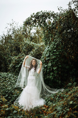 Closeup shot of elegant, brunette bride posing under veil closeup. Bride portrait wedding makeup fashion bride. Beautiful bride in veil. Newlyweds wedding photoshoot.