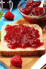 Toast bread with homemade raspberry jam or marmalade on table served with butter for breakfast or brunch