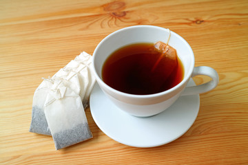 One cup of freshly brewed hot tea with tea bag on the wooden table