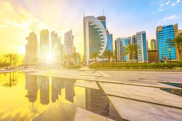 Fototapeta premium Malownicze wysokie góry Doha West Bay w świetle słońca odbijające się w wodzie parku w centrum miasta. Nowoczesne wieżowce panoramę Doha w Katarze, na Bliskim Wschodzie, Półwyspie Arabskim w Zatoce Perskiej.
