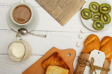 A cup of coffee, fresh bread, toast on a white woody background. Morning breakfast fresh bread with a cup of coffee. View from above.