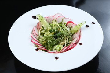 restaurant dish, green salad with radishes, arugula and cucumbers, healthy food, for the menu