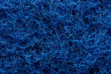 The texture of the surface of interwoven blue threads of abrasive synthetic fiber.