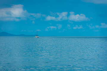 Obraz premium Segelboot treibt unter leicht bewölktem Himmel