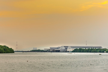 large industrial factory building side coast of sea or river in evening and soft orange sunshine