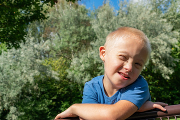 Happy and smiling boy with down syndrome poses for a portrait outdoors.
