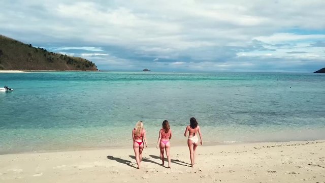 Drone shot of girls in bikini going for a swim in Fiji with turquoise water