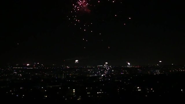 Fireworks exploding over night city skyline during new year's eve celebrations