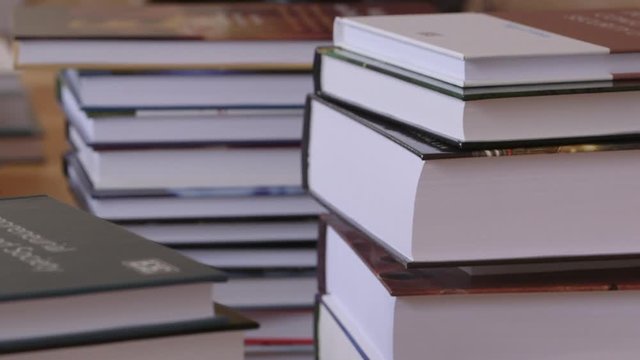 Pull focus onto a stack of hardback text books, CLOSE UP