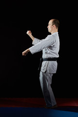 Fototapeta na wymiar In karategi, an athlete does formal karate exercises on red and blue tatami