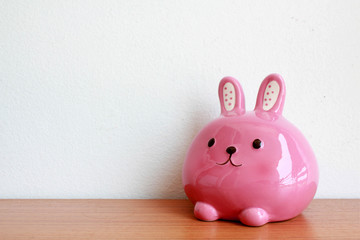 Pink rabbit bank on wooden table,close up,select focus with shallow depth of field