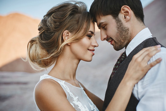 Fashionable and beautiful couple, happy blonde model girl with stylish hairstyle, in a white lace dress and stylish handsome man in the trendy suit