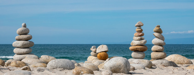 Zen stone towers are piled high on a mostly sunny day along the Pacific Coast of central California at Spanish Bay Beach,  on the famous 17 mile drive, next to Asilomar State Park.