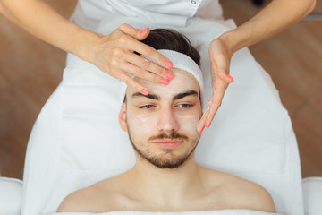 Obraz na płótnie Canvas Unshaven man having cosmetic mask care in spa salon, side, top view - Image