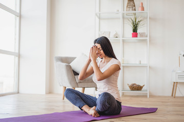 Young adult female doing yoga and smiling at home