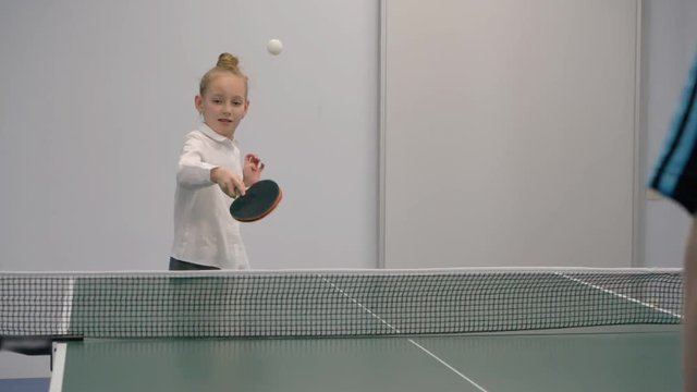 Young girl playing ping pong slow motion. Sport girl teenager playing tennis at ping pong table in sport club
