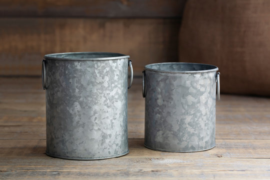 Mockup of two silver metal containers next to a burlap sack on a brown wooden background.