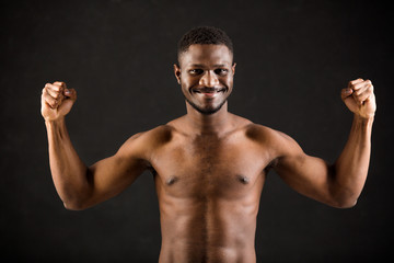 Fototapeta na wymiar handsome african man on black background showing his muscles