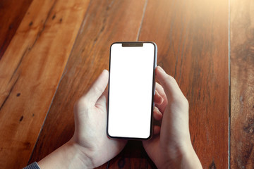 hand holding phone on wood table with blank screen.