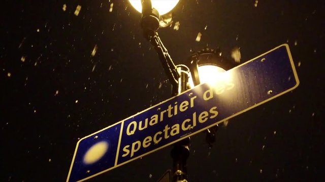 Street sign of quartier des spectacles in downtown Montreal at night during snow storm 4k