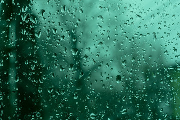 Background image of rain drops on a glass window. Emerald tone