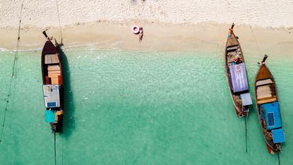 Drone pictures aerial view of a girl on the beach with crystal clear water, a floating boat and boats on a sunny day © naproadavida_npv
