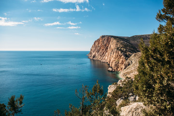Obraz premium Beautiful Crimean rocky coast with high cliff and sea in sunny day, summer nature landscape for travel and rest